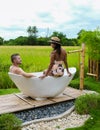 men and women in bath tub outside on vacation at a homestay in Thailand with green rice paddy field Royalty Free Stock Photo