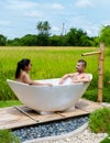 men and women in bath tub outside on vacation at a homestay in Thailand with green rice paddy field Royalty Free Stock Photo