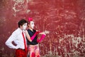 Couple mimes looking aside on the background of a red wall.