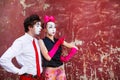 Couple mimes looking aside on the background of a red wall