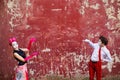 Couple mimes point to center on a background of a red wall