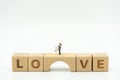 Couple Miniature 2 people standing on wood word LOVE. Day 14 meets Valentine Day. Red heart is the promise of love. using as