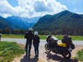 Couple of motorcyclists adventure riders. Green meadow in Zgornje Jezersko, to Kamnik-Savinja Alps on a sunny summer day in