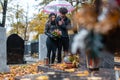 Couple mourning a deceased loved one on cemetery in fall