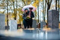 Couple mourning a deceased loved one on cemetery in fall