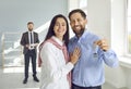 Portrait of happy young Caucasian family joyfully and contentedly showing keys to their new home. Royalty Free Stock Photo