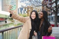 A couple of multiracial happy girls having fun takng a photo with a cellphone. Two young women smiling doing a selfie Royalty Free Stock Photo