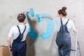 Couple in new home during repair works painting wall together. Happy family holding paint roller painting wall with blue Royalty Free Stock Photo