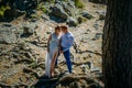 A couple of newlyweds stand in the wild nature and gaze at each other. In the background, a big tree and huge wooden roots