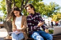Couple not talking to each other typing on mobile phones sitting in the bench on the street Royalty Free Stock Photo