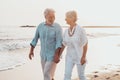 Couple of old mature people walking on the sand together and having fun on the sand of the beach enjoying and living the moment. Royalty Free Stock Photo