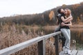 A couple on the old wooden bridge at a lake on autumn day in park. Forest on background. Happy togather, copy space for text. Royalty Free Stock Photo