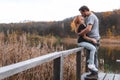 A couple on the old wooden bridge at a lake on autumn day in park. Forest on background. Happy togather, copy space for text. Royalty Free Stock Photo