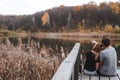 A couple on the old wooden bridge at a lake on autumn day in park. Forest on background. Selective focus, copy space for text. Royalty Free Stock Photo