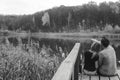 A couple on the old wooden bridge at a lake on autumn day in park. Forest on background. Selective focus, copy space for text. Royalty Free Stock Photo