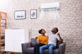 Couple Operating Air Conditioner At Home Royalty Free Stock Photo