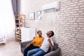 Couple Operating Air Conditioner At Home Royalty Free Stock Photo