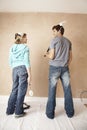 Couple With Paint Roller Looking At Each Other Against Wall Royalty Free Stock Photo