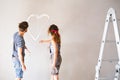 Couple painting heart on the wall in their house. Royalty Free Stock Photo