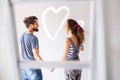 Couple painting heart on the wall in their house.