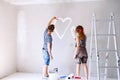 Couple painting heart on the wall in their house. Royalty Free Stock Photo