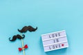 Couple paper mustache props on stick and light box with text Love is love on blue background. Concept Homosexuality gay love. Royalty Free Stock Photo