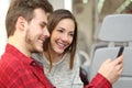 Couple of passengers sharing a smart phone inside a train