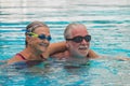 Couple of pensioners seniors in the pool swimming and having fun together hugged - healthy and fit concept doing exerise together Royalty Free Stock Photo