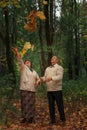 Couple pensioners walk in an autumn park tossing up yellow leaves Royalty Free Stock Photo
