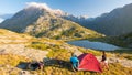 Couple of people setting up a camping tent on the mountains, time lapse. Summer adventures on the Alps, idyllic lake and summit.