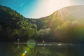 A couple of people slowly floating on the river on the sup-board, against the mountains and blue sky