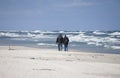 A couple of people strolling on the beach on a  rough spring Baltic Sea on a sunny day Royalty Free Stock Photo