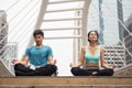 couple perform lotus hand pose yoga in city