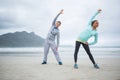 Couple performing stretching exercise on beach Royalty Free Stock Photo