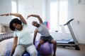 Couple performing stretching exercise on fitness ball in bedroom