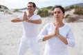 Couple performing yoga on beach