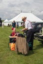 Couple in period dress setting up a picnic behind classic vintage car