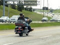 A couple of persons on a motorcycle riding it on a highway
