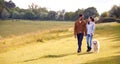 Couple With Pet Golden Retriever Dog Walking Along Path Across Field In Countryside Royalty Free Stock Photo