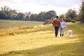 Couple With Pet Golden Retriever Dog Walking Along Path Across Field In Countryside Royalty Free Stock Photo