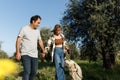 Couple with pet ,golden retriever dog, walking along path across field in countryside Royalty Free Stock Photo