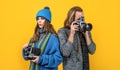 Couple of photojournalists hold photo cameras taking photograph yellow background, paparazzi