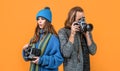 Couple of photojournalists hold photo cameras taking photograph yellow background, paparazzi