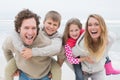 Couple piggybacking kids at the beach Royalty Free Stock Photo