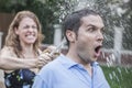 Couple playing with a garden hose and spraying each other outside in the garden, man has a shocked look, close-up Royalty Free Stock Photo