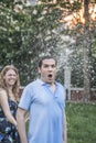 Couple playing with a garden hose and spraying each other outside in the garden, man has a shocked look Royalty Free Stock Photo