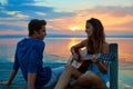 Couple playing guitar in sunset pier at dusk beach Royalty Free Stock Photo