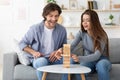 Couple playing Jenga while sitting in the living room