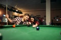 Couple plays in billiard room, male player aiming Royalty Free Stock Photo