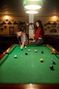 Couple plays in billiard room, male player aiming Royalty Free Stock Photo